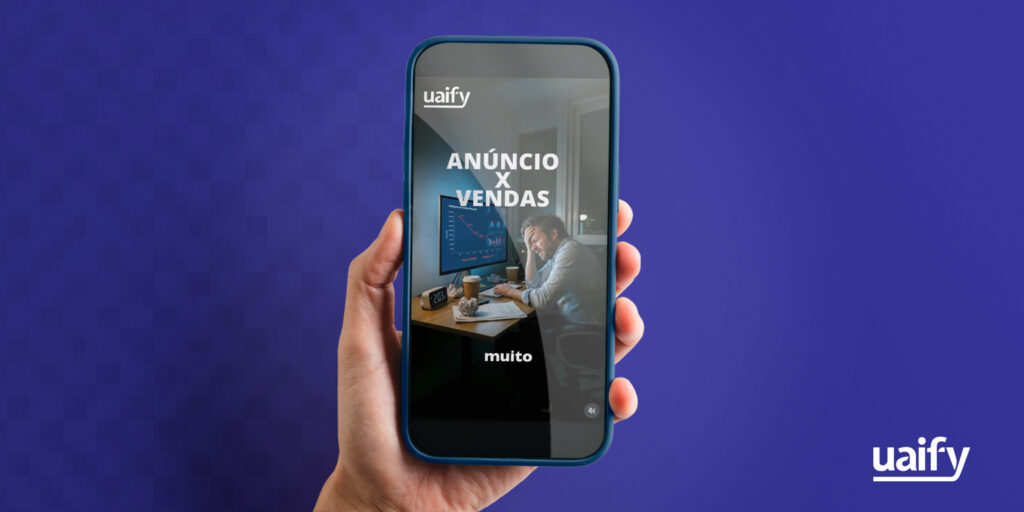 Uma mão segura um smartphone contra um fundo azul escuro. Na tela do celular, é exibido um conteúdo vertical (criativos) com o logotipo da 'uaify' no topo, o texto 'ANÚNCIO X VENDAS' em letras grandes e brancas, e a imagem de um homem estressado olhando para um gráfico com uma linha vermelha em queda no monitor do computador. A palavra 'muito' aparece na parte inferior da tela. O logotipo branco da 'uaify' também está presente no canto inferior direito do fundo da imagem principal.