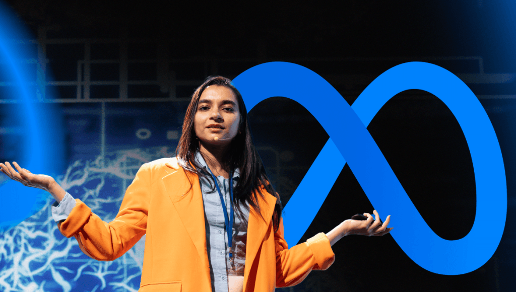 Uma mulher de blazer laranja e blusa azul fala gesticulando em um palco escuro, com um grande logotipo azul da Meta (um símbolo de infinito estilizado) projetado atrás dela e gráficos abstratos em azul ao fundo. Ela usa um microfone de lapela e parece estar dando uma palestra ou apresentação.