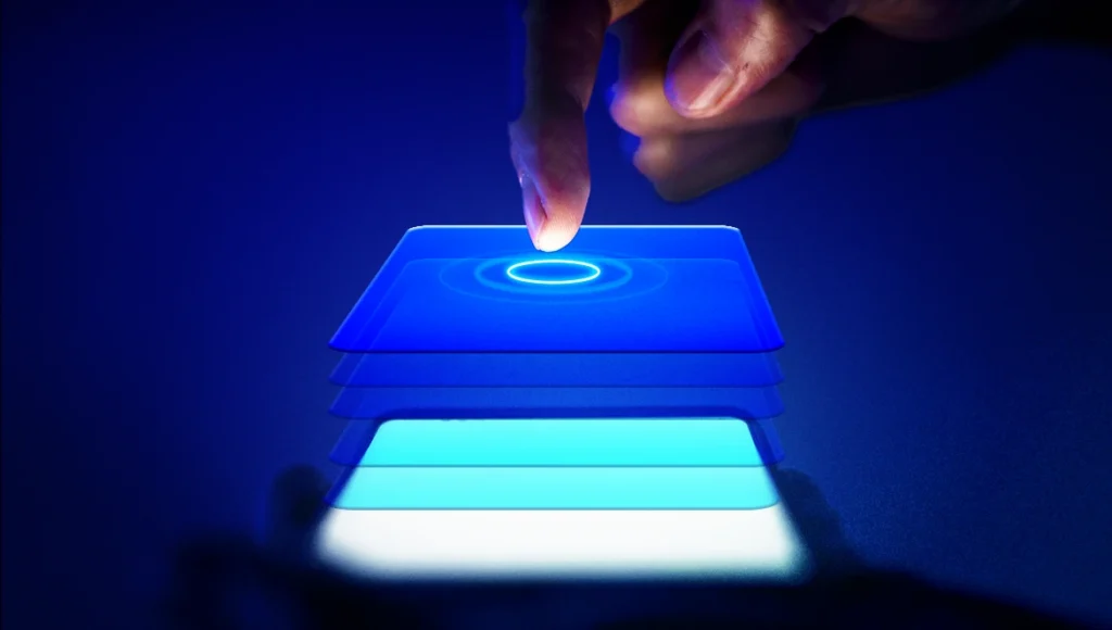 Dedo tocando uma tela holográfica azul dividida em cinco camadas flutuantes e iluminadas, simbolizando tecnologia, UX ou processos em camadas.